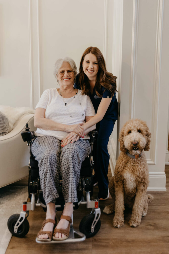 nurse posing with elderly woman and golden doodle