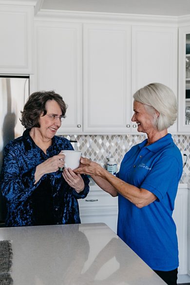 caregiver serving coffee to elderly woman